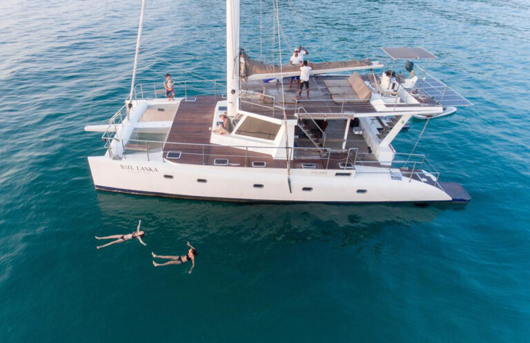 Leute schwimmen neben Katamaran