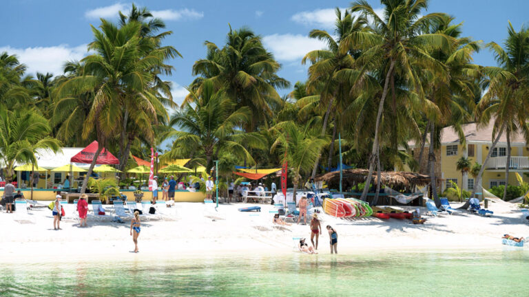 Bahamas Strand mit Menschen und bunten Surfbrettern, Kanus und Restaurants