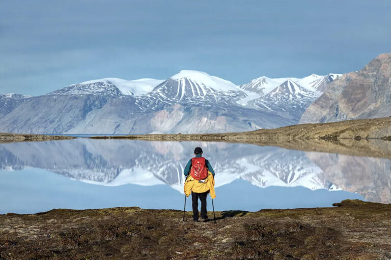 Wanderer vor See mit Bergspiegelung auf dem Wasser
