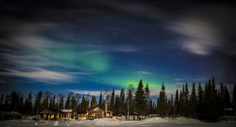 Holzhütten im Wald mit Nordlichtern