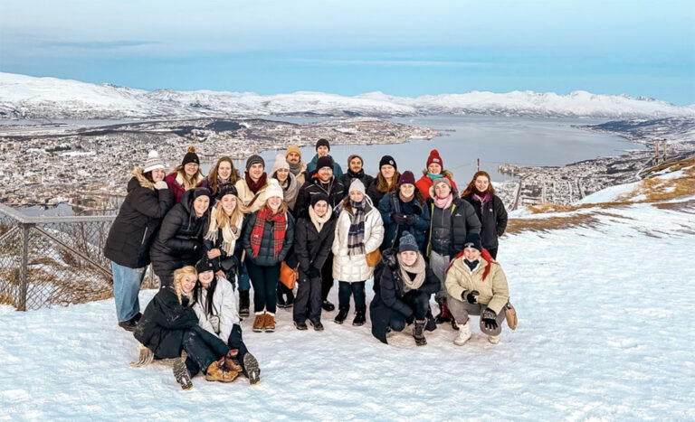 Gruppenbild in Tromsø auf dem berg Storsteinen mit Blick auf die stadt im Schnee im Hintergrund