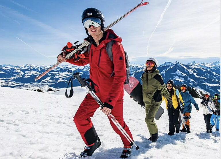 Gruppe geht mit abgeschnallten Skiern und Snowboards den Berg hoch