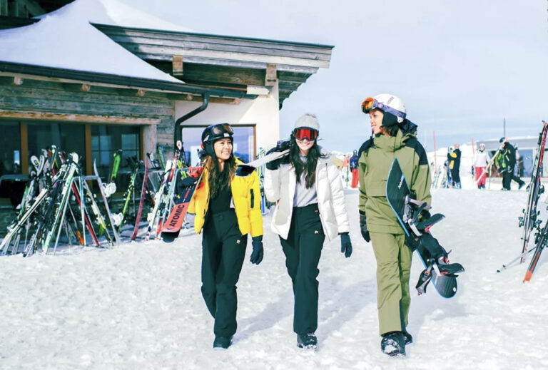 3 Mädels mit Ausrüstung vor Skihütte