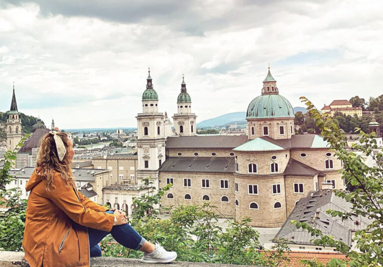 Reisende auf Mauer mit Blick auf den Salzburger Dom