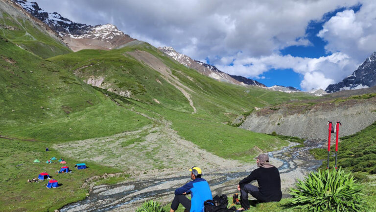 Zwei Wanderer blicken hinab auf das Zeltcamp im Tal