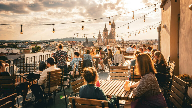 Gäste auf Dachterrasse mit Getränken und Blick auf Krakau