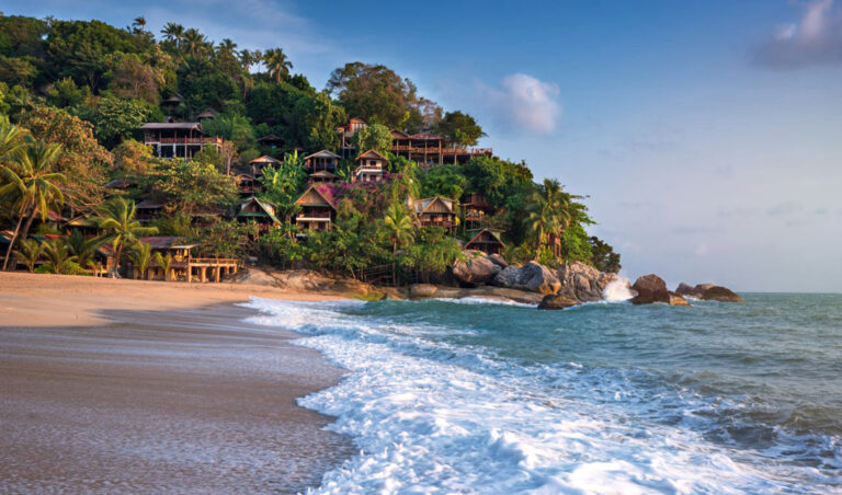 Strand auf Koh Phangan mit Häuschen auf grüner Anhöhe