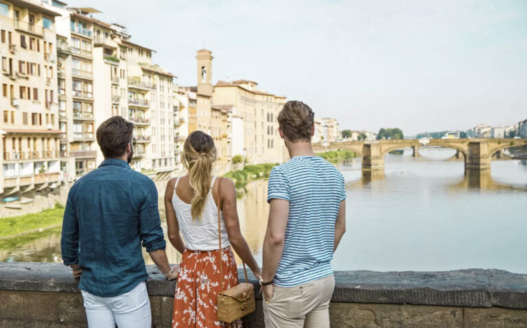 3 Reisende blicken auf eine Brücke in Florenz