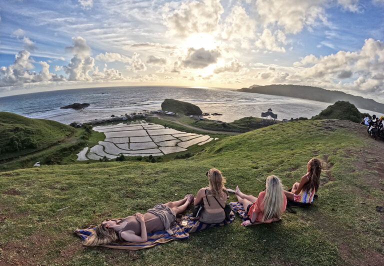 Junge Leute liegen auf einer Wiese am Meer