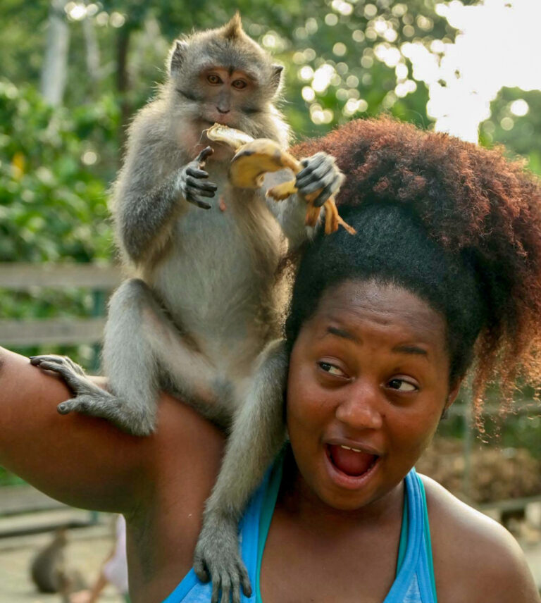 Affe sitzt auf der Schulter einer erschrockenen Touristin
