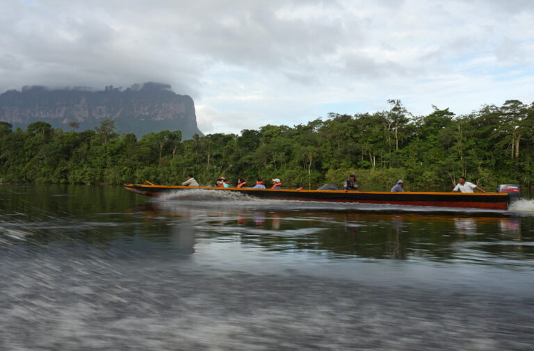 Bootsausflug in der Grand Sabana, im Hintergrund Regenwald und ein wolkenverhangener Tafelberg