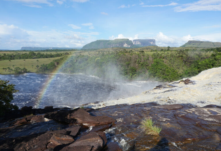 Regenbogen über Stromschnellen, im Hintergrund Tafelberge