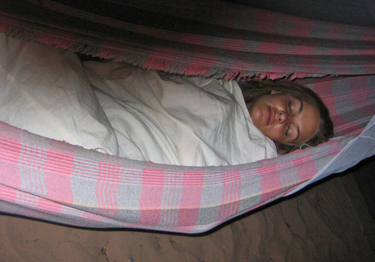 Reisende gemütlich eingekuschelt in rosa-grau karierter Hängematte