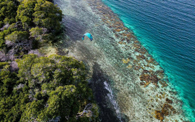 Kitesurfer über Küste des Mochima Nationalparks mit Blick auf das Korallenriff