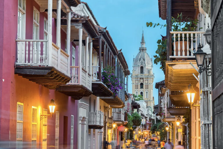 Beleuchtete Straße mit Kolonialhäusern und Blick auf einen Kirchturm in Cartagena