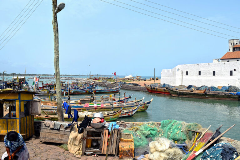 Bunte Fischerboote im Hafen vor der Burg von Elmina