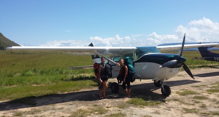 Zwei Rucksackreisende am kleinen Flugzeug