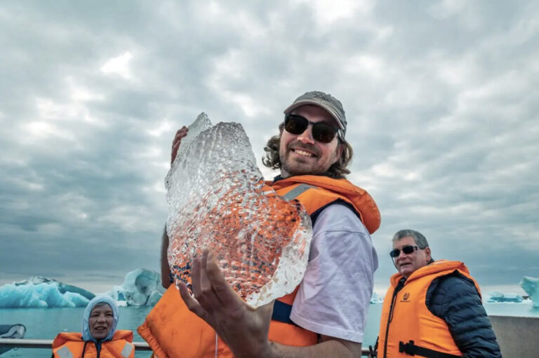 Reisender mit Rettungsweste hält Eisbrocken hoch