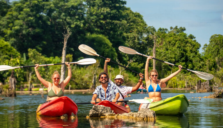Junge Leute in Kajaks mit hochgereckten Paddeln