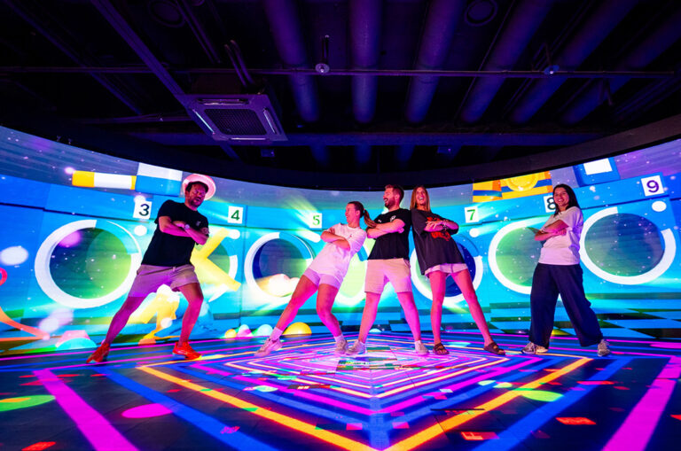 Junge Leute machen K-Pop Tanzschritte vor Neon-Lichter-Hintergrund
