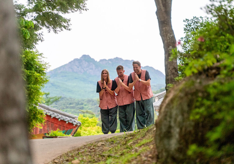 3 Reisende in Tempelkleidung mit aneinandergelegten Händen