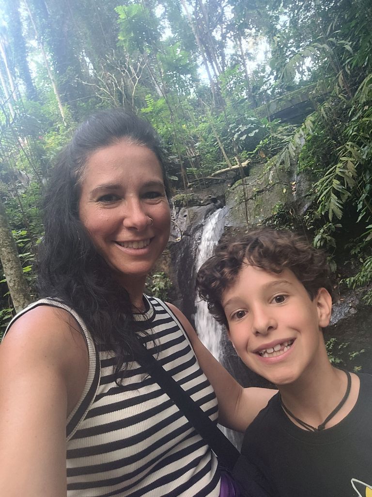 Mutter und Sohn vor einem Wasserfall in Indonesien