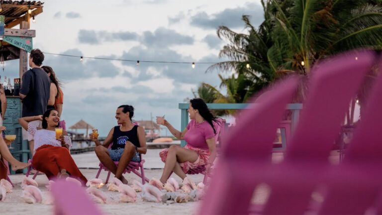 Junge Leute in pinken Holzliegen am Strand auf Caye Caulker