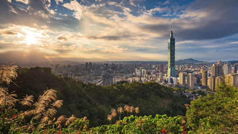 Blick auf die Hochhäuser von Taipei von grünen Hügeln aus, Sonne bricht durch Wolken