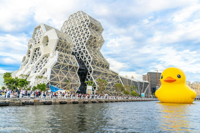 Futuristisches Gebäude am Wasser mit riesigem Quietscheentchen