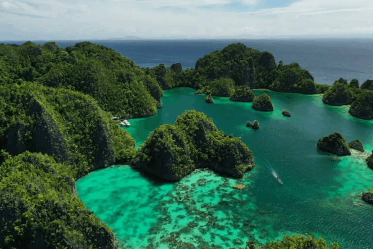 Luftaufnahme der grünen Karstinseln und türkisfarbenen Lagunen von Raja Ampat, Indonesien – spektakuläre Naturkulisse beim Raja Ampat Urlaub unter Segeln