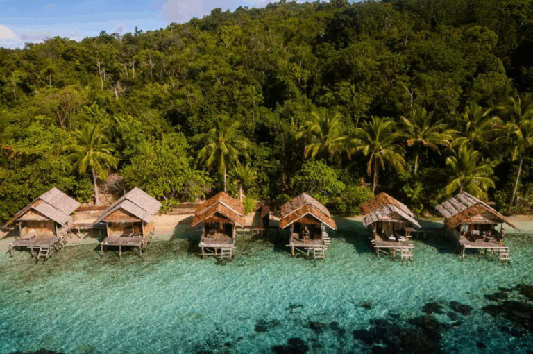 Traditionelle Wasserbungalows über türkisfarbenem Meer in Raja Ampat, Indonesien – nachhaltige Unterkunft inmitten tropischer Natur während eines Raja Ampat Urlaubs